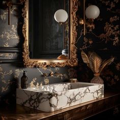 a bathroom sink sitting under a mirror next to a wall mounted faucet in front of a gold framed mirror