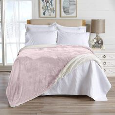 a white bed with pink comforter and pillows