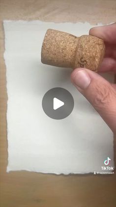 a person holding a cork in front of a piece of paper