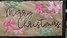 a sign that says merry christmas with pink bows and green leaves on the side of it