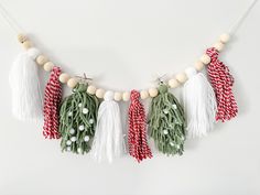 the garland is decorated with green and red tassels, white beads, and wooden beads