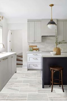 a kitchen with white cabinets and black counter tops, an island in the middle is flanked by two stools