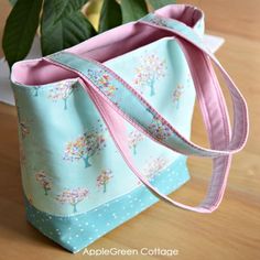 a blue and pink bag sitting on top of a wooden table next to a potted plant