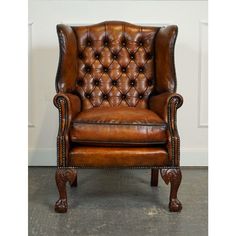 an old fashioned leather chair with wooden legs