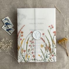 an envelope with flowers on it next to postage stamps and some dried plants in the background