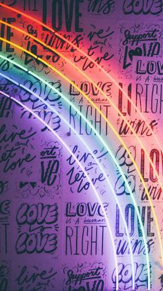 the word love is written in different languages on a wall with a rainbow colored light