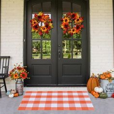 the front door is decorated with pumpkins and wreaths