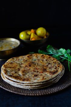 three flat breads on a plate next to bowls of fruit