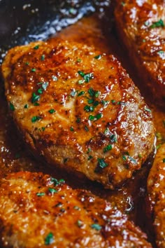 some meat is cooking in a pan with sauce and parsley on the top side