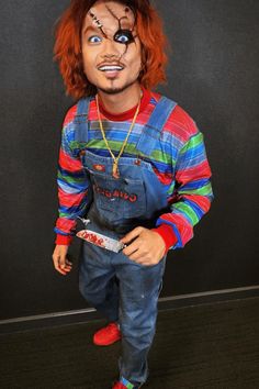 a creepy clown with red hair and blue overalls holding a knife in his hand