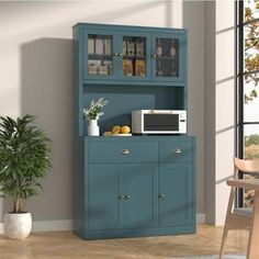 a blue cabinet with a microwave on top and a potted plant next to it