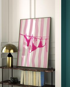 a pink and white painting hanging on a wall next to a shelf with some books