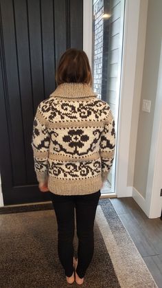 a woman standing in front of a door wearing a sweater and black pants with an animal print on it