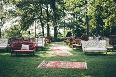 chairs and couches are set up in the grass for an outdoor wedding ceremony with rugs on the ground