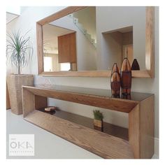 a wooden shelf with two vases on it and a large mirror over the top