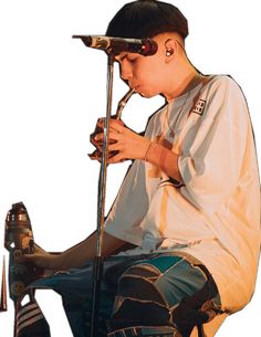 a young man sitting on top of a stool holding a microphone in his hand and looking down