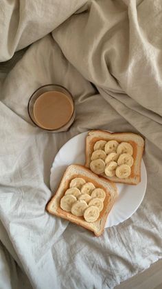 two pieces of toast with banana slices on it and a cup of coffee in the background