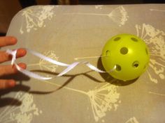 a green ball with holes on it being held by someone's hand over a table