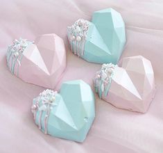 four blue and pink heart shaped candys on a white bed sheet with light pink sheets