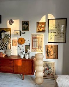 a room filled with lots of framed pictures and art on the wall above a dresser