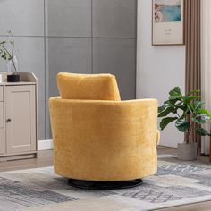 a yellow chair sitting on top of a rug in a living room next to a potted plant