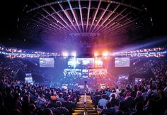 an arena full of people watching and playing video games on the big screen televisions