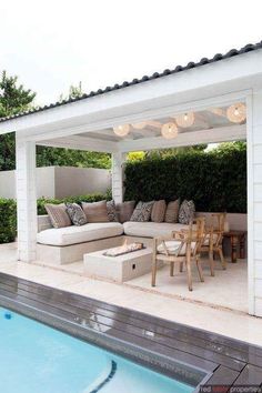 an outdoor living area with couches and tables next to a swimming pool in the backyard