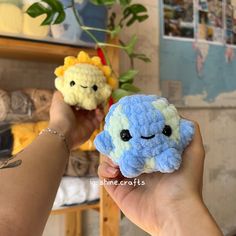 two small crocheted stuffed animals are being held in front of each other by someone's hand