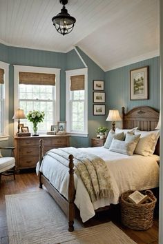 a bedroom with blue walls and white bedding, two windows, wooden dressers