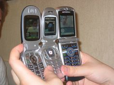 a person holding three cell phones in their hands