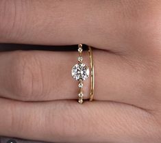 a woman's hand wearing a gold ring with two diamonds on it and a diamond band