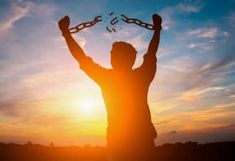 a man is holding his hands up in the air with chains over his head as the sun sets behind him