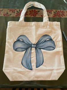 a white bag with a blue bow painted on the front and side, sitting on a table