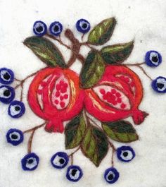 embroidered pomegranates and leaves on white cloth with blue eyes in the center