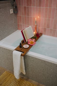 a bathtub with candles, books and flowers in it