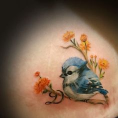 a blue bird sitting on top of a tree branch with flowers around it's neck