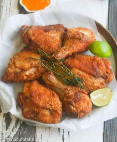 fried chicken wings on a white plate with limes and ketchup