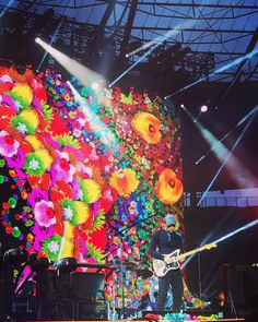 a man that is standing on a stage with a guitar in front of some lights