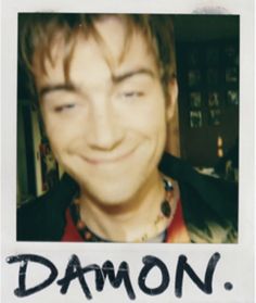 a young man smiling with the word demon written on his face in front of him