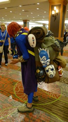 two people in costume are looking at items on the floor as others walk by them