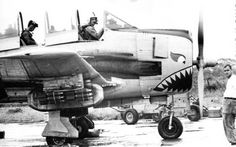 an old black and white photo of people standing around a plane with shark teeth on it