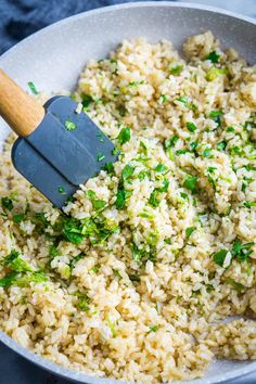 rice and herbs being stirred in a pan