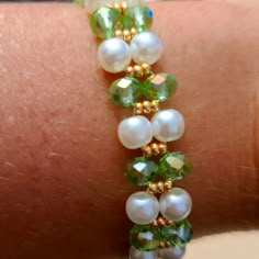 a close up of a person's arm wearing a bracelet with pearls and green glass beads