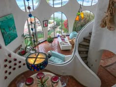 a living room filled with furniture and lots of windows next to a spiral stair case