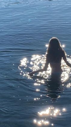 a woman is in the water with her back turned to the camera and she has long hair