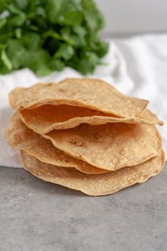 three tortilla chips stacked on top of each other with lettuce in the background