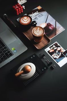 an open laptop computer sitting on top of a desk next to two cups of coffee