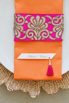 an orange and pink place setting on a white plate