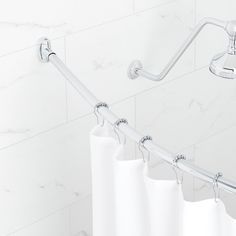 a white shower curtain hanging from the side of a bathtub with handles on it