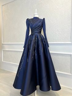 Step into the spotlight with our Elegant Navy Evening Gown. This stunning piece boasts an exquisite high neckline and delicately sculpted long sleeves, providing both grace and sophistication. Made from premium, luxurious fabric, it offers a comfortable yet fitted silhouette that flatters your figure.The gown features intricate embellishments cascading from the waistline, adding a touch of sparkle and elegance to your look. Its full, flowing skirt creates a dramatic A-line shape that moves gracefully with every step, making it perfect for formal events, galas, and special occasions.Designed to make a statement, this navy evening gown is a timeless addition to any wardrobe. Pair it with your favorite heels and statement jewelry to complete the ensemble. Embrace elegance and sophistication w Muslim Evening Dresses, Long Sleeve Evening Gowns, Arabian Women, Moroccan Kaftan, Braut Make-up, Moroccan Caftan, Elegant Lady, فستان سهرة